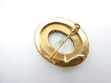 an image of a gold broochle with a white stone in the center