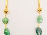 a close up of a necklace with green stones on it