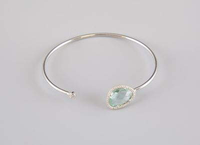 a close up of a silver bang bracelet with a green stone on it