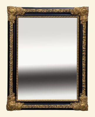 un miroir au cadre or et noir richement décoré, accroché à un mur blanc