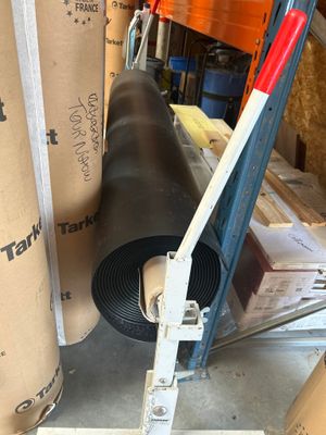 un rouleau de ruban adhésif posé par terre à côté d'un rouleau de carton