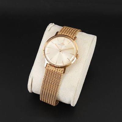 une photo d'une montre-bracelet en or posée sur un tissu blanc