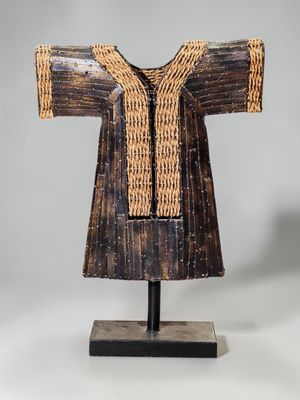 une sculpture en bois représentant la robe d'une femme, posée sur un socle