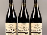 trois bouteilles de vin sont alignées sur une table