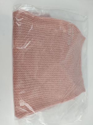 a pink sweater in a plastic bag on a table