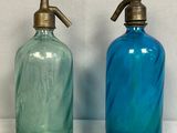 deux bouteilles en verre bleues et vertes placées l'une à côté de l'autre