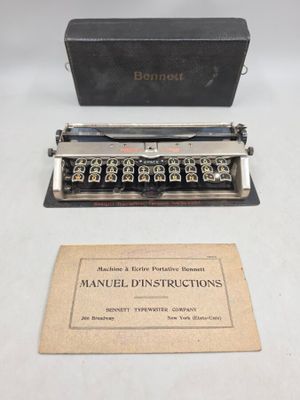 une vieille machine à écrire manuelle posée sur une table, à côté d'une boîte