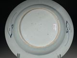 a blue and white plate on a stand with a black background