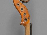 a close up of a violin with a wooden stick on a gray surface