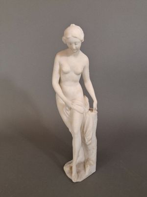 statue of a woman sitting on a rock with her hands in her pockets