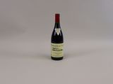 une bouteille de vin rouge posée sur une table blanche