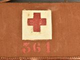 an old brown suitcase with a red cross on it