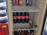 a refrigerator that has a lot of sodas and soda bottles in it