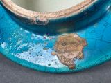 a close up of a blue vase with a gold leaf on it
