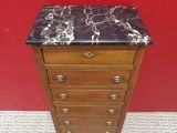 a small marble top chest of drawers against a red wall