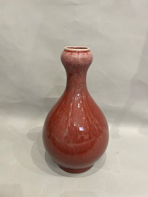 a red vase that is sitting on a white surface