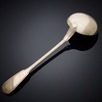 silver spoon and spoon rest on a black surface with a black background