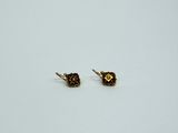 une paire de petites boucles d'oreilles en or posées sur une surface blanche
