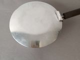 a silver pan with a black handle on a table
