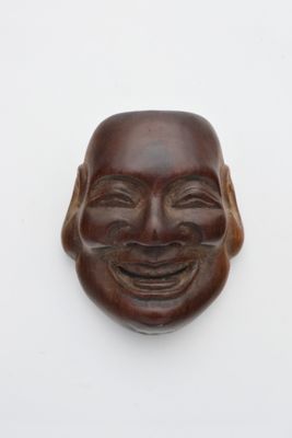 masque en bois représentant un homme souriant sur fond blanc
