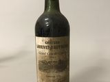 une vieille bouteille de vin posée sur une table blanche