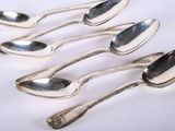 six silver spoons are lined up in a row on a white surface