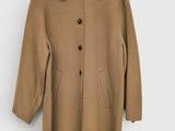 Ce manteau est en laine et comporte des boutons au niveau du col.