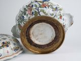 a vase with a lid sitting next to a pillow