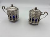 pair of silverplated teapots with blue glass in the shape of a birdcage