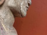 statue d'une femme avec une fleur dans les cheveux devant un mur rouge