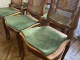 four chairs with green upholstered cushions sit on a wooden floor