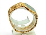 a gold bracelet with a green stone on a stand