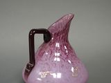 a purple vase with a brown handle on a gray surface