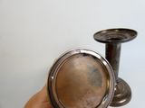 a hand holding a silver vase with a silver lid