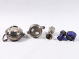 three silver teapots and two blue glass vases on a white surface
