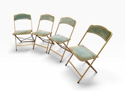 quatre chaises pliantes alignées sur une surface blanche