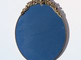 a blue mirror hanging on the wall with a gold frame