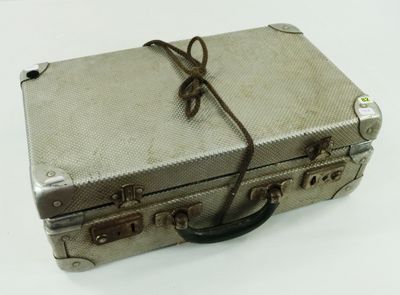 a silver piece of luggage that is tied up on a white surface