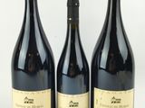 trois bouteilles de vin posées les unes à côté des autres sur une surface blanche