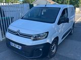 une camionnette blanche garée sur un parking près d'une clôture