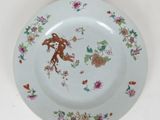 a white plate with a bird and flowers on it