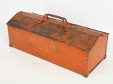 an old red metal tool box with a handle sitting on a white surface