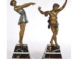 une paire de figurines en bronze représentant un garçon et une fille, posées sur des socles en marbre