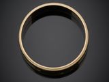a close up of a gold wedding ring on a black surface