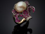 a white pearl and pink sapphire ring on a black surface