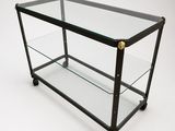 an image of a glass and brass coffee table on wheels