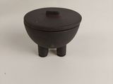 a small black bowl with a lid on a white surface