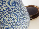 un vase bleu et blanc posé sur une table avec un miroir