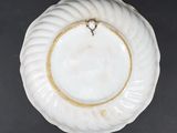 a white plate with a gold rim on a black table