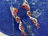 une paire de boucles d'oreilles en rubis et diamants posées sur une plaque de pierre bleue